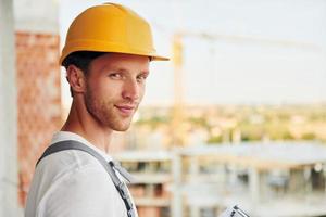 View from the side. Young man working in uniform at construction at daytime photo