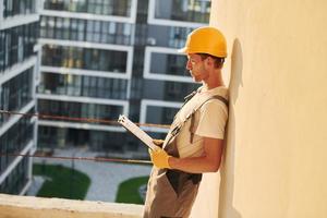 hermoso fondo joven que trabaja en uniforme en la construcción durante el día foto