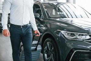 Partical view. Man in formal clothes is with luggage indoors near the car photo