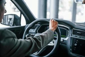 View from behind. Woman testing new car. Sitting indoors in modern automobile photo