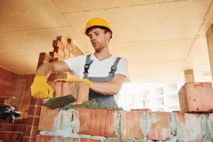 View from the side. Young man working in uniform at construction at daytime photo