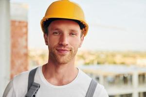 Building of modern city. Young man working in uniform at construction at daytime photo