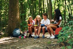 sentarse y descansar. niños paseando por el bosque con equipo de viaje foto