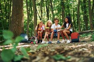 sentarse y descansar. niños paseando por el bosque con equipo de viaje foto