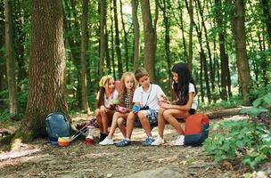 Taking a break. Kids strolling in the forest with travel equipment photo