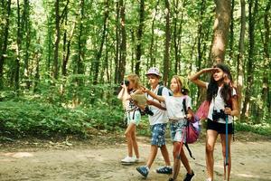 Summertime weekend. Kids strolling in the forest with travel equipment photo