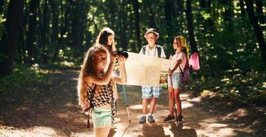 With touristic equipment. Kids strolling in the forest photo