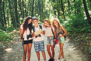 Front view. Kids strolling in the forest with travel equipment photo