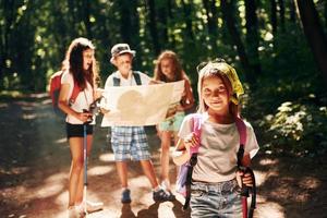 posando para la cámara. niños paseando por el bosque con equipo de viaje foto