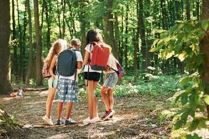 Kids strolling in the forest with travel equipment photo