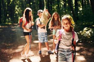 Posing for the camera. Kids strolling in the forest with travel equipment photo