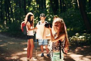 With touristic equipment. Kids strolling in the forest photo