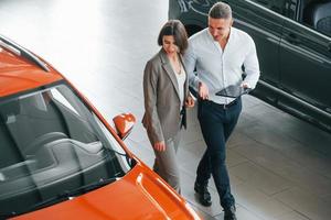 View from above. Man in formal wear helping customer with choice of the automobile photo