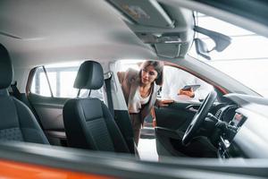 Looking at interior. Man in formal wear helping customer with choice of the automobile photo