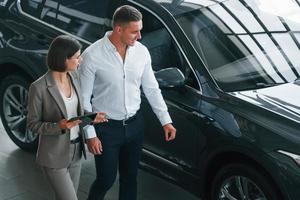 View from above. Man in formal wear helping customer with choice of the automobile photo