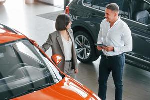 View from above. Man in formal wear helping customer with choice of the automobile photo