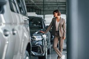 Modern technology. Woman is indoors near brand new automobile indoors photo