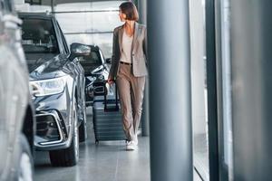 Tourist with lugagge. Woman is indoors near brand new automobile indoors photo