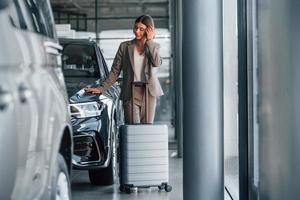 Posing for a camera. Woman is indoors near brand new automobile indoors photo