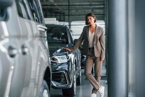 Modern technology. Woman is indoors near brand new automobile indoors photo