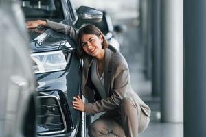 abrazando el coche. la mujer está adentro cerca de un automóvil nuevo adentro foto