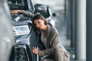 abrazando el coche. la mujer está adentro cerca de un automóvil nuevo adentro foto