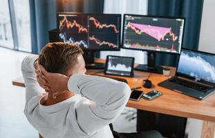 Taking a rest. Young businessman in formal clothes is in office with multiple screens photo