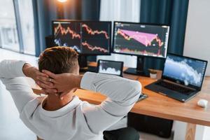 Taking a rest. Young businessman in formal clothes is in office with multiple screens photo