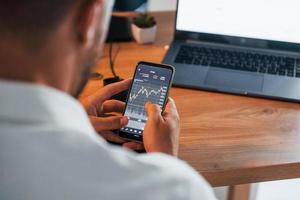 Graphs and diagrams. Young businessman in formal clothes is in office with multiple screens photo