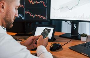 Graphs and diagrams. Young businessman in formal clothes is in office with multiple screens photo