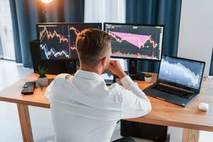 Taking a rest. Young businessman in formal clothes is in office with multiple screens photo