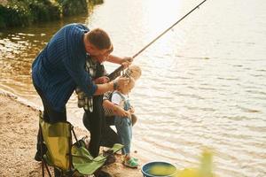 Learning to fishing. Father and mother with son and daughter together outdoors at summertime photo