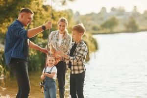 Weekend activities. Father and mother with son and daughter on fishing together outdoors at summertime photo