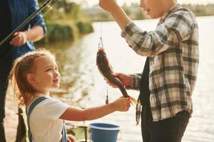 Father with son and daughter on fishing together outdoors at summertime photo