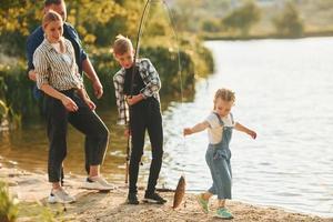 Weekend activities. Father and mother with son and daughter on fishing together outdoors at summertime photo