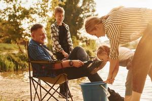 Big catch. Father and mother with son and daughter on fishing together outdoors at summertime photo