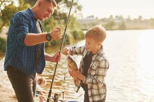 Showing the catch. Father and son on fishing together outdoors at summertime photo