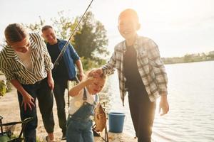 escena rural. padre y madre con hijo e hija pescando juntos al aire libre en verano foto