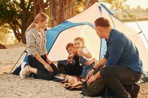 Sitting on the ground. Family of mother, father and kids is on the camping photo