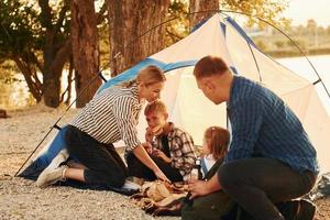 Sitting on the ground. Family of mother, father and kids is on the camping photo