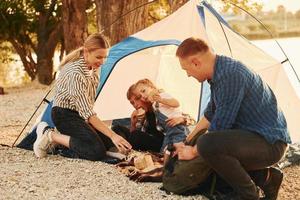 sentado en el suelo. la familia de madre, padre e hijos está acampando foto