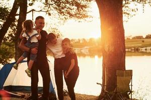 Evening time. Family of mother, father and kids is on the camping photo