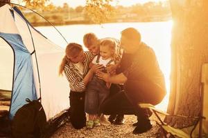 hermosa luz del sol. la familia de madre, padre e hijos está acampando foto
