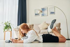 Modern technologies. Female teenager with blonde hair is at home at daytime photo