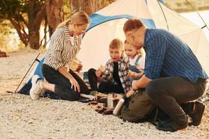 Active time spending. Family of mother, father and kids is on the camping photo