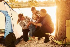 hermosa luz del sol. la familia de madre, padre e hijos está acampando foto