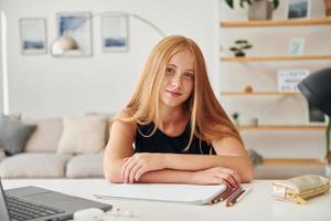 posando para una cámara. una adolescente con cabello rubio está en casa durante el día foto