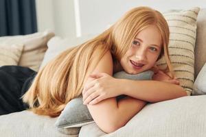 Portrait of female teenager with blonde hair that is at home at daytime photo