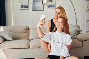 Sitting on the floor. Female teenager with her mother is at home at daytime photo