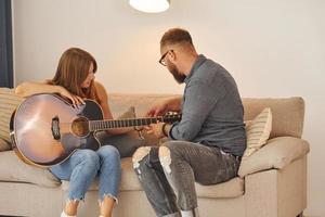Guitar teacher showing how to play the instrument to young woman photo